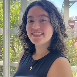 Portrait of Camila smiling in front of a window with trees in the background