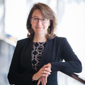 Portrait of Melissa Hunt smiling and leaning against a railing in the NBS building